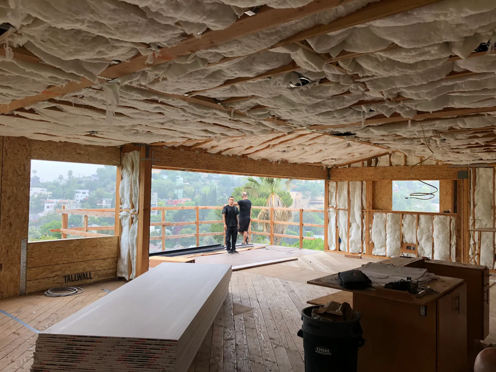 Board stacked in a hillside room under an insulated ceiling, with the city visible past the deck.