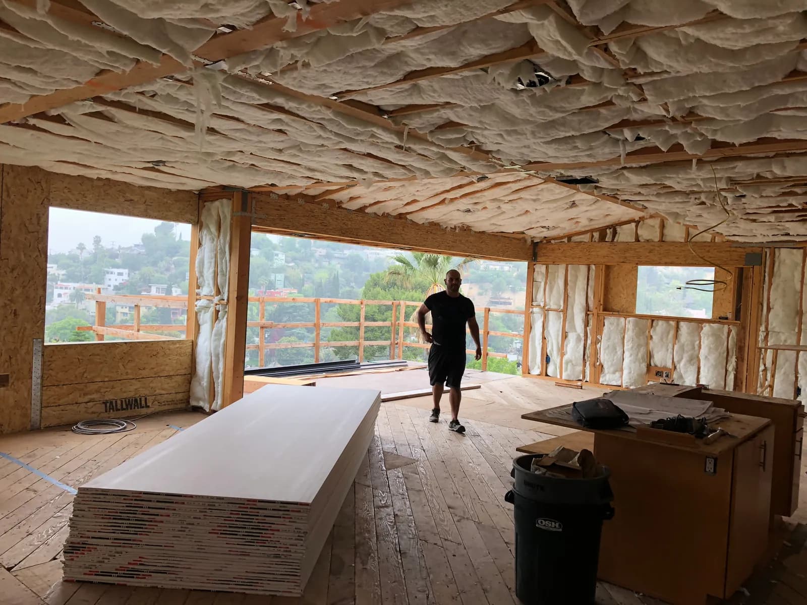 A hillside room in framing and insulation, opening onto a deck with a view across the hills.