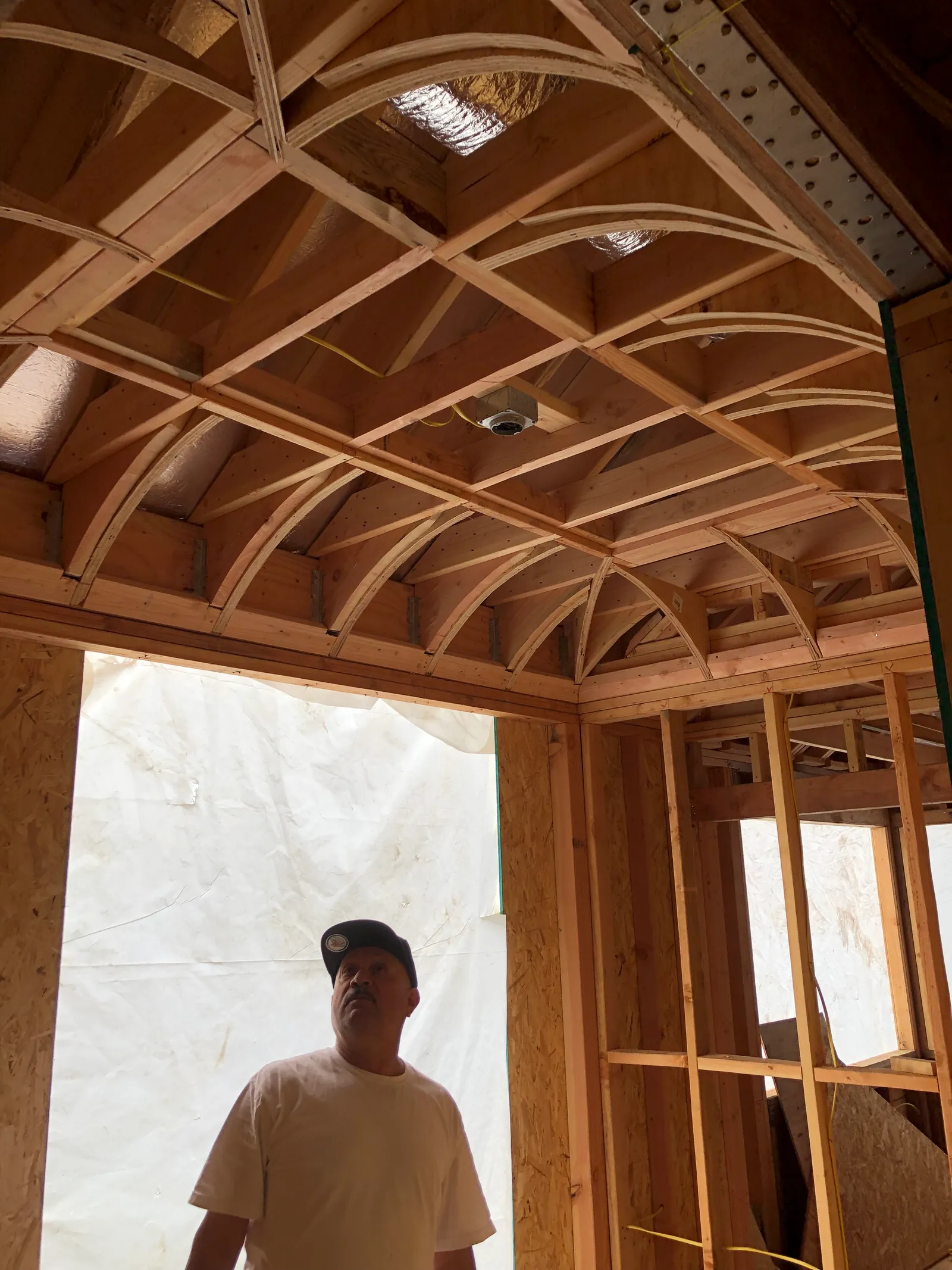A crew member below the barrel-vaulted timber framing.