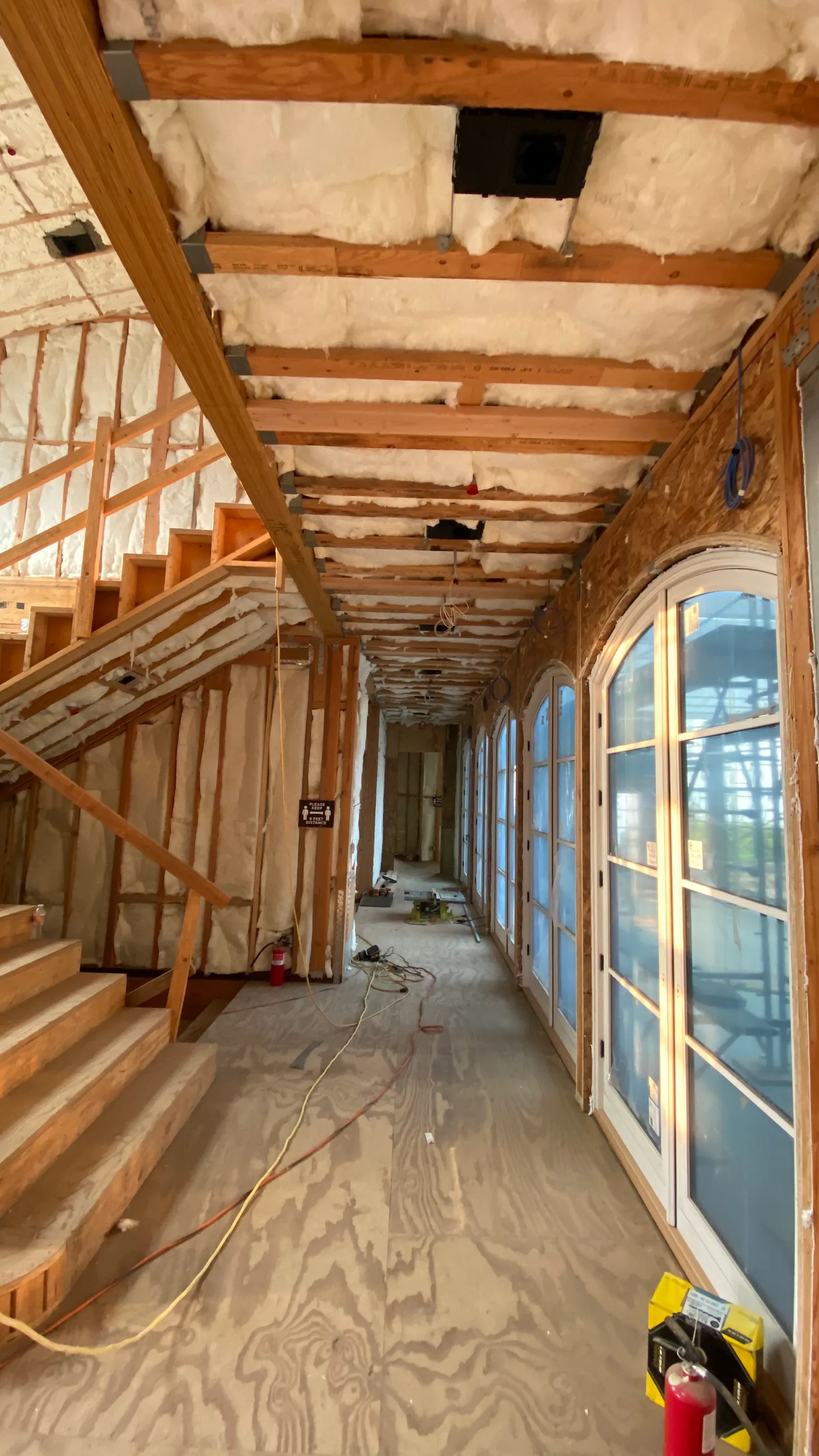 A corridor of arched openings in framing, insulation overhead.