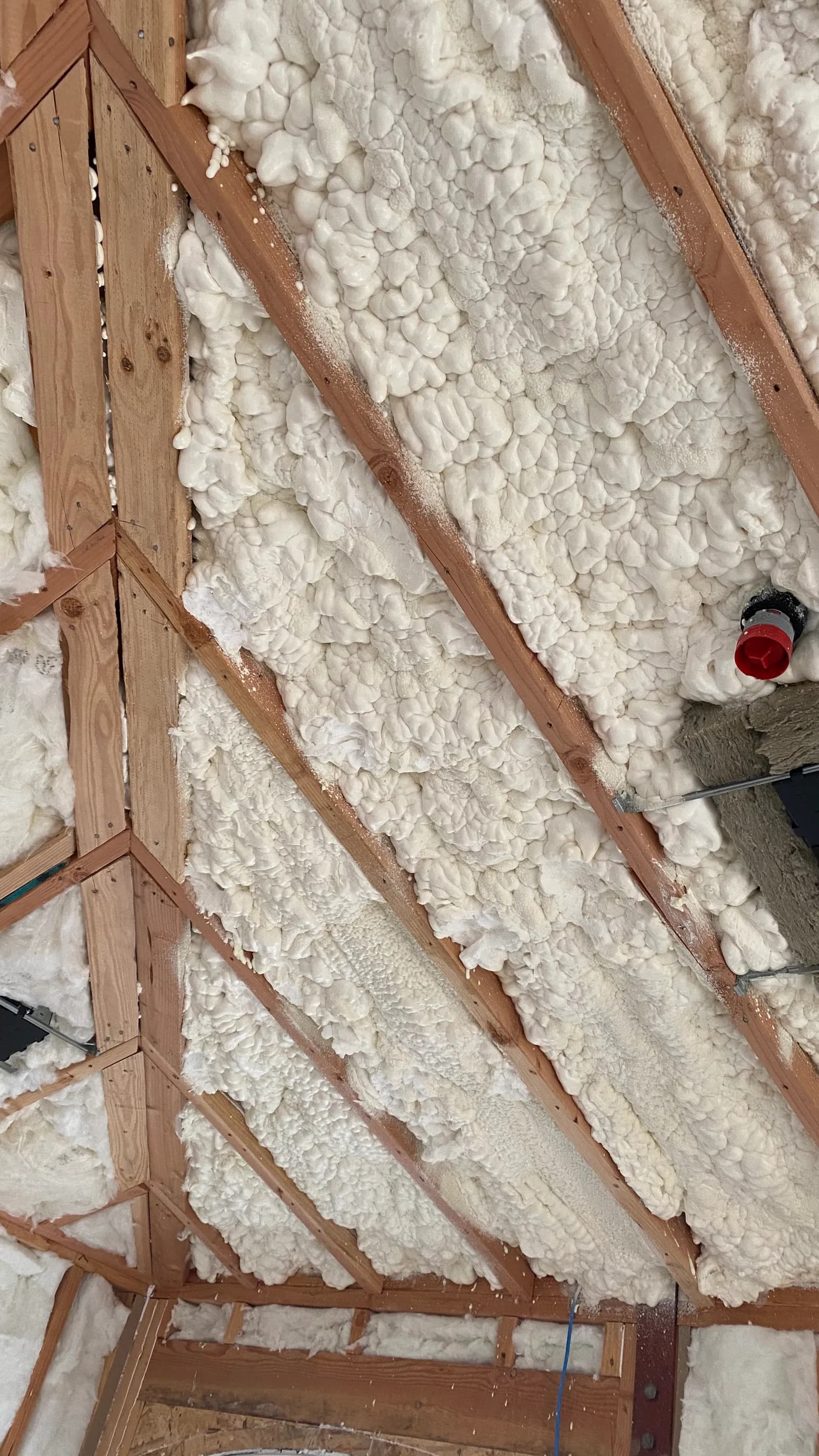 Spray-foam insulation between studs and rafters at close range.