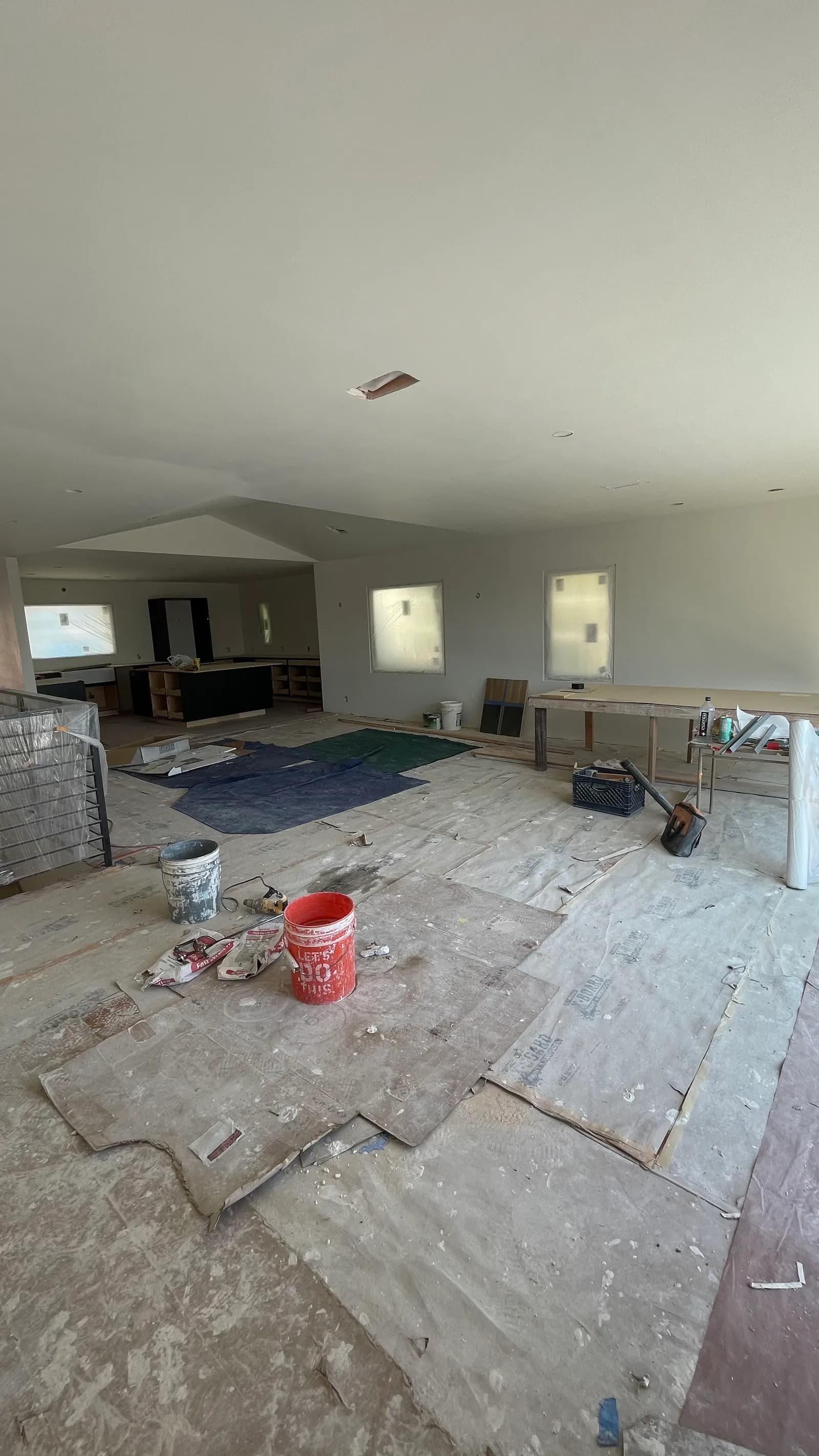 Open living and kitchen space with walls and ceiling closed in, floor protection still down.